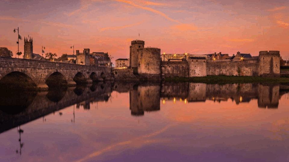 Stone castle and bridge reflected in a calm river at sunset, with an orange and purple sky—perfect scenery for relaxing Autumn Hotel Breaks.