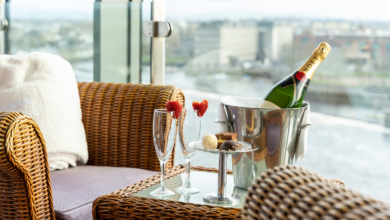 A wicker chair beside a glass table with two champagne flutes, chocolate truffles, and a bottle of champagne in an ice bucket—perfect for celebrating Valentine's in Limerick while overlooking the cityscape.