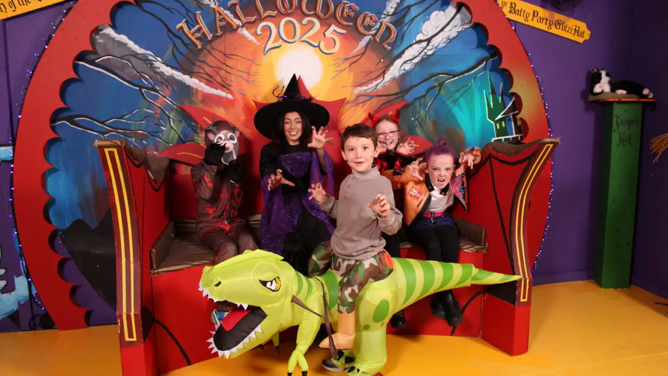 Halloween celebration with a witch and kids, one is costumed as a dinosaure